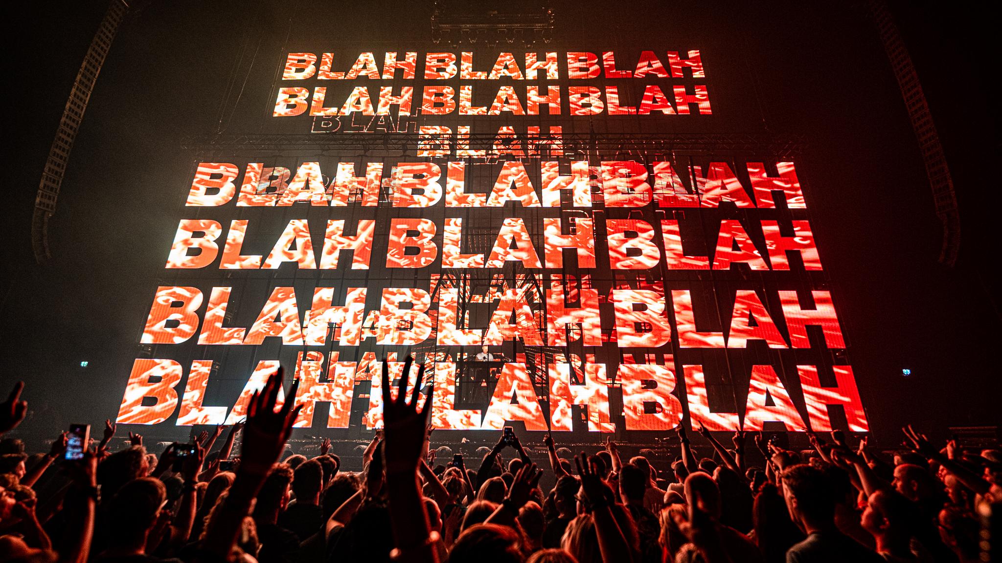 Armin van Buuren fans dancing in front of a screen full of Blah Blah Blah lyrics 