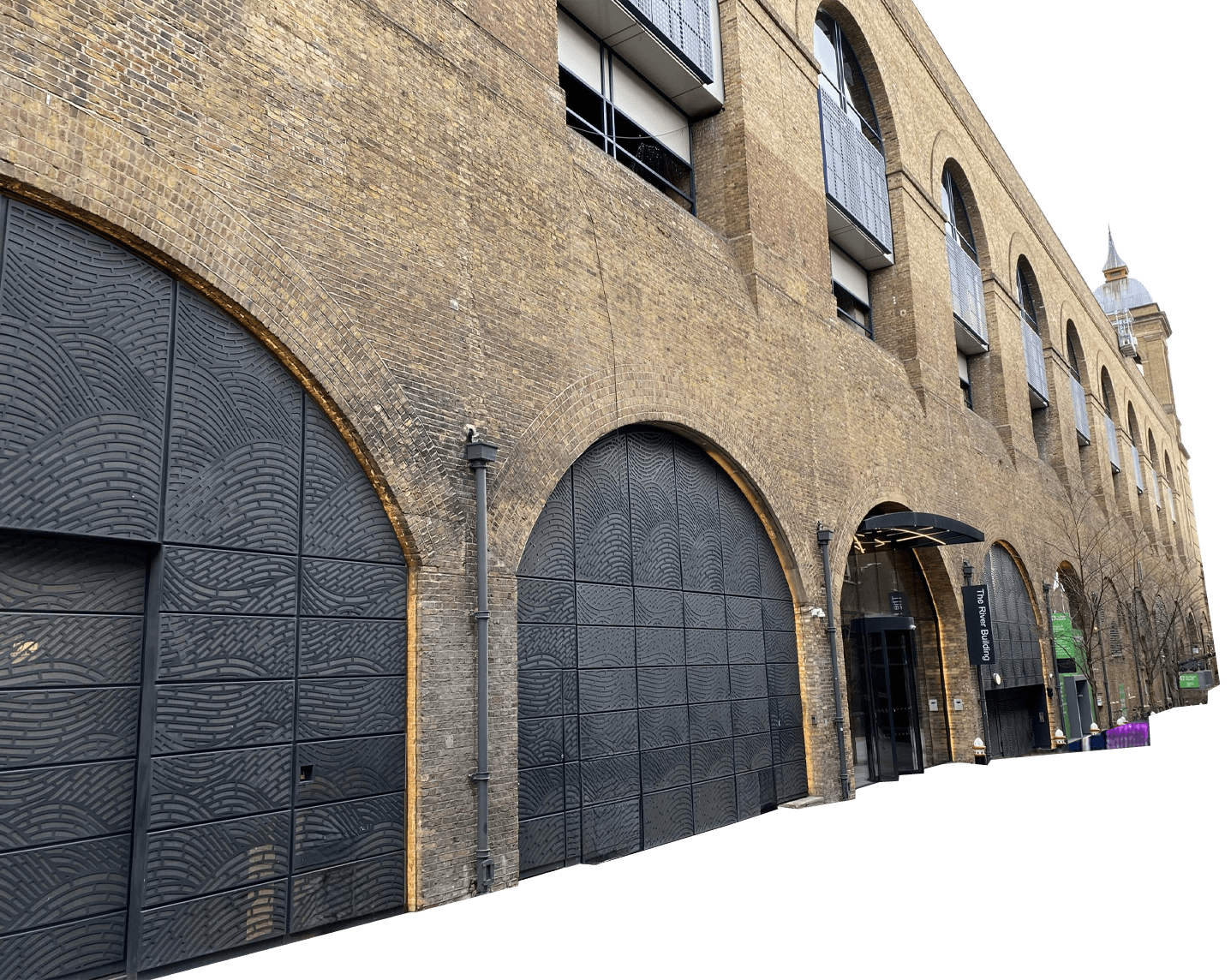 The steel yard with arched entrances, some covered by large patterned metal doors. One entrance leads to a lobby area beneath a black canopy.